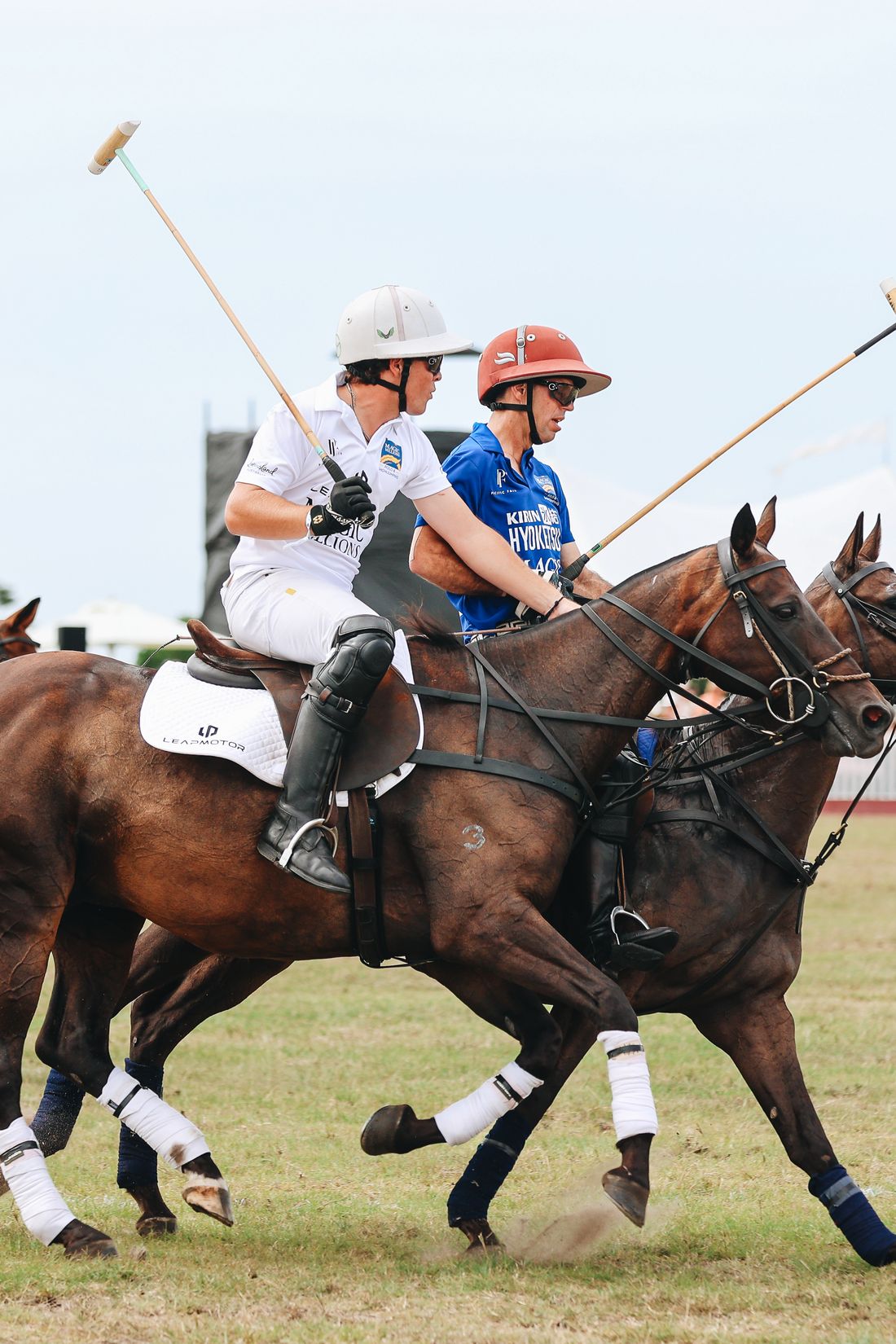 Two polo players riding off shoulder to shoulder mid-match